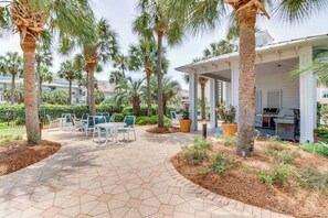 Un espace patio agrémenté de carreaux hexagonaux, de mobilier d’extérieur, de palmiers et d’un barbecue.
