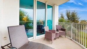 Ein Balkon mit Korbstühlen, einer Glastür, die zu einem Innenbereich führt, und Blick ins Freie.