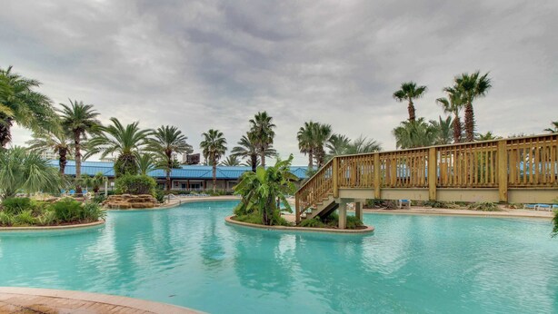 Ein Pool mit Palmen und einer Holzbrücke.