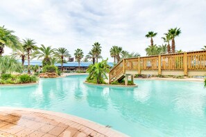 A swimming pool with palm trees and a wooden bridge. - Resort condo with balcony, shared pool, hot tub, gym, tennis, WiFi, and AC (Destin)