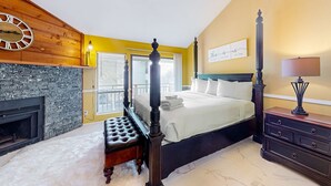 A bedroom with a four-poster bed, a stone fireplace, and a large wall clock. - Inviting townhouse with on-site pool, updated interior, & W/D (St. George Island)