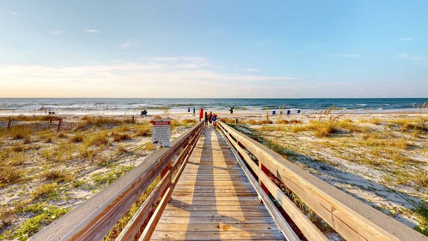 A wooden boardwalk leading to the beach with a warning sign. - Inviting townhouse with on-site pool, updated interior, & W/D (St. George Island)