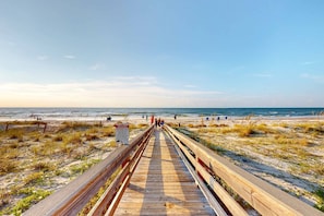 A wooden boardwalk leading to the beach with a warning sign. - Inviting townhouse with on-site pool, updated interior, & W/D (St. George Island)