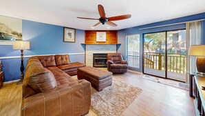 A living room with a sectional sofa, a fireplace, a ceiling fan, and a view of the outdoors. - Inviting townhouse with on-site pool, updated interior, & W/D (St. George Island)