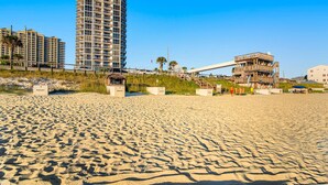 Une plage avec un immeuble de grande hauteur, un chantier de construction et une structure en bois.