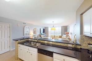 A kitchen with a black countertop, white cabinets, and a dishwasher. - Lake-view 5th-floor resort condo with outdoor pool, gym, balcony, & washer & dryer (Destin)