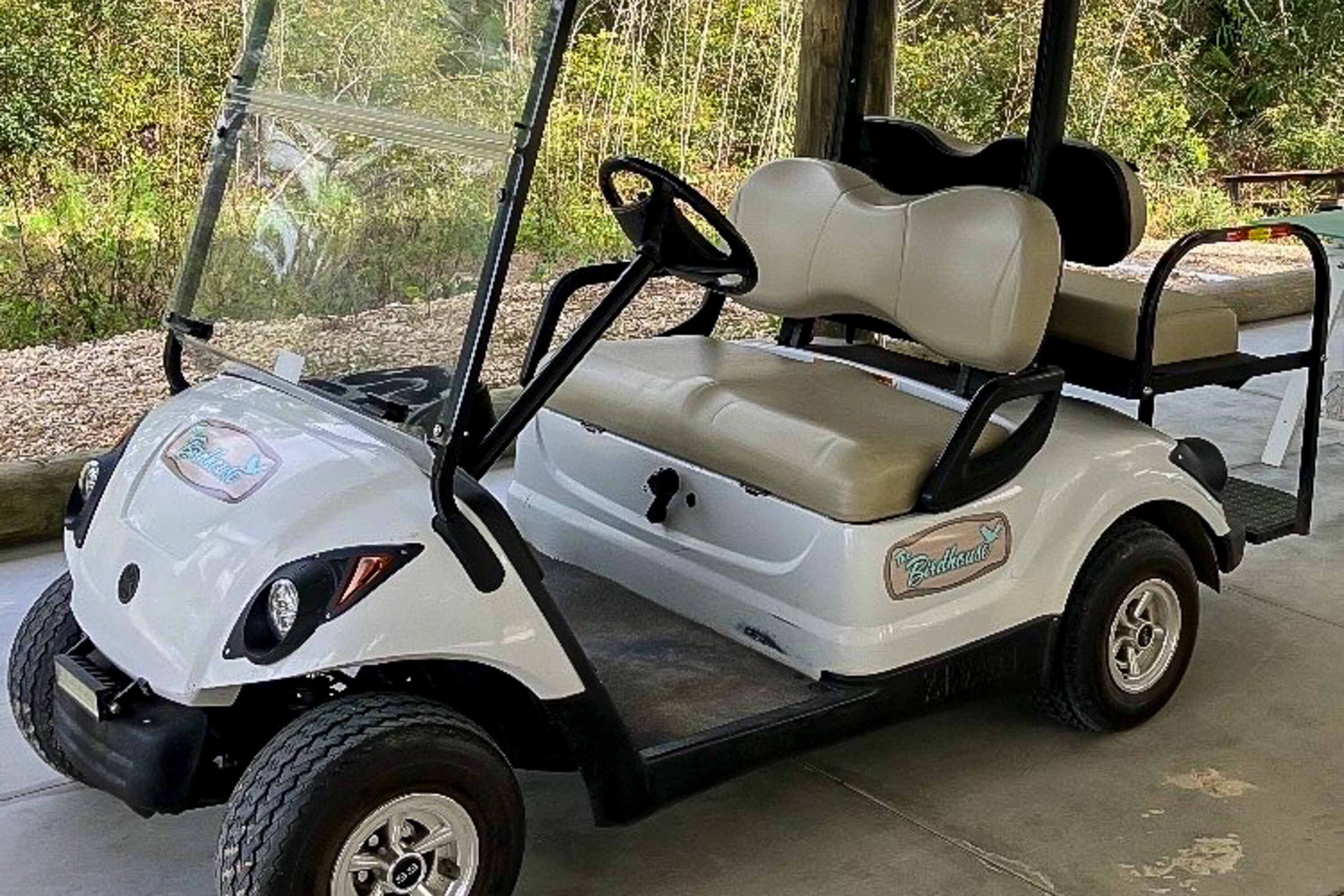 Ein Golfmobil mit beiger Sitzbank und einem Logo an der Seite.