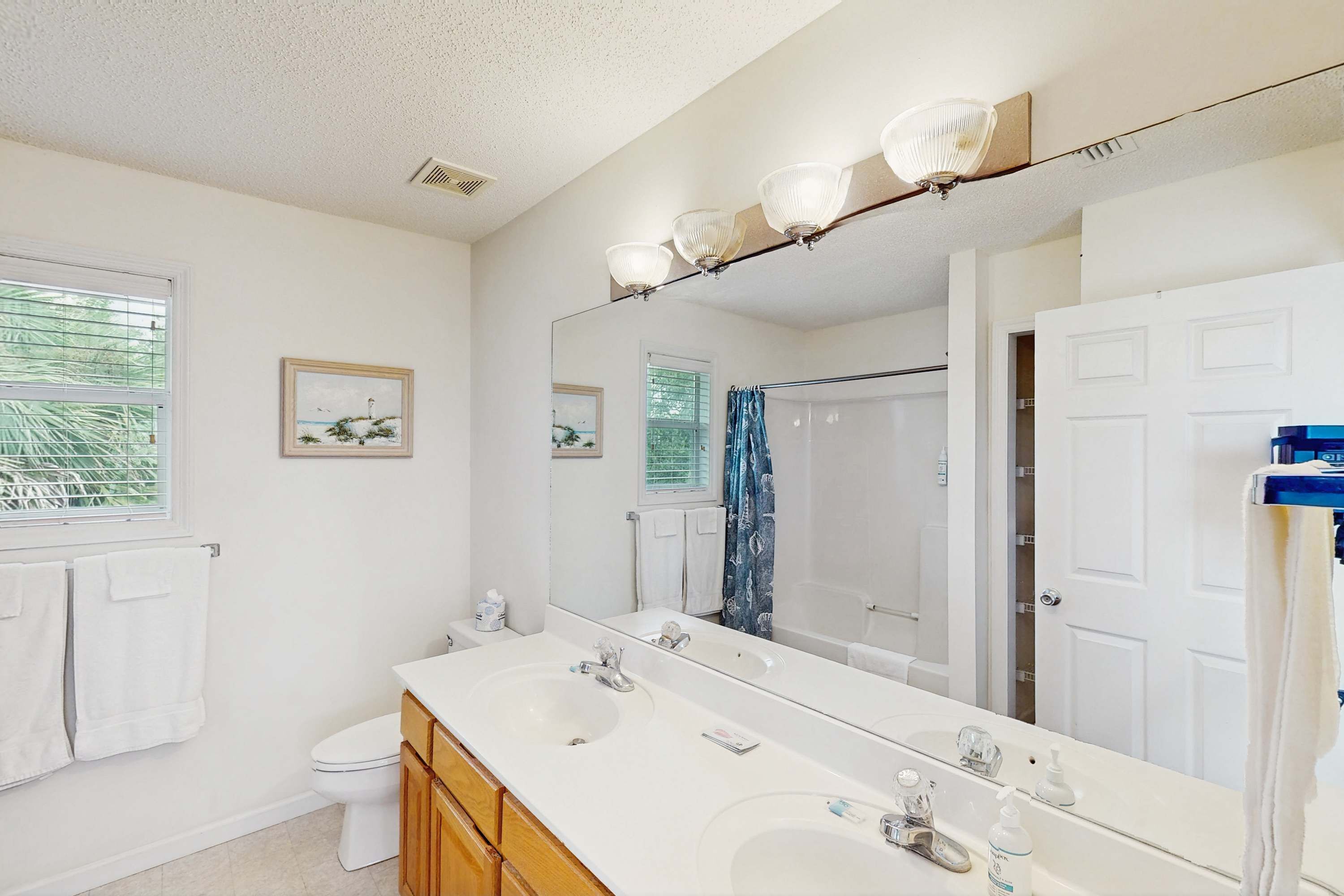 A bathroom with a double sink, a large mirror, and a shower.