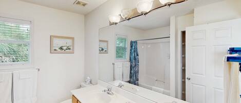 A bathroom with a double sink, a large mirror, and a shower.