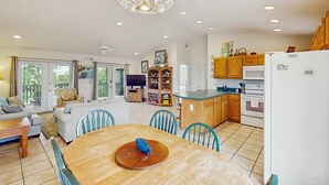 A spacious living area with a wooden dining table, a sofa, and a TV in the background. - Dog-friendly home near the beach with spacious living area, porch & sundeck (Port St. Joe)