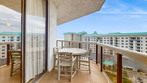 Varanda com mesa e cadeiras, com vista para um horizonte urbano com edifícios altos.