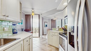 Uma cozinha moderna com ilha central, forno embutido e uma geladeira grande.