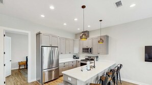 Une cuisine moderne dotée d’appareils électroménagers en acier inoxydable, d’un îlot central et de tabourets de bar.