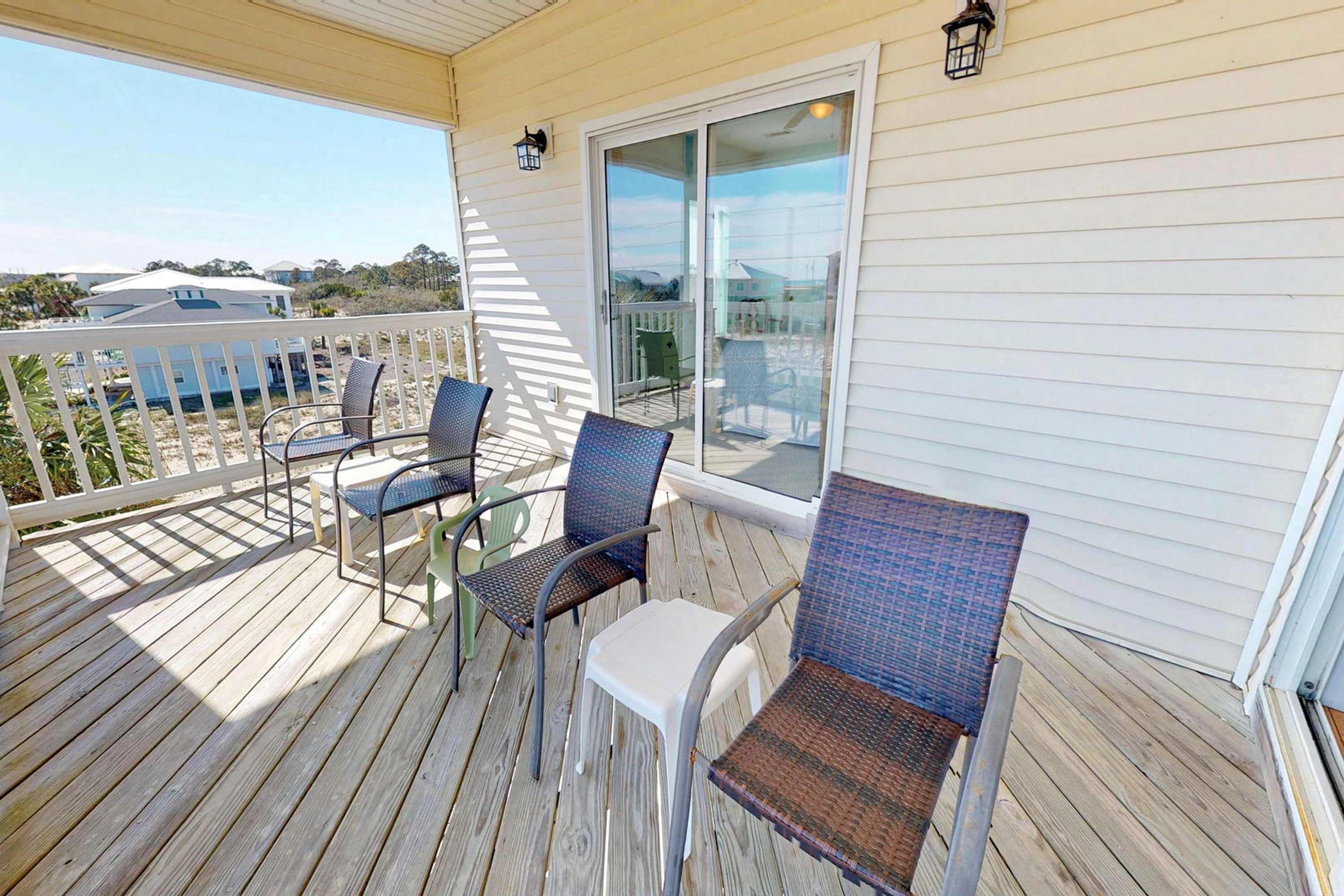 Un espace extérieur abrité, doté d’une terrasse en bois, de chaises en métal et d’une table en verre.