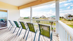 Overdekt terras met vier groene stoelen en uitzicht op een woonwijk.