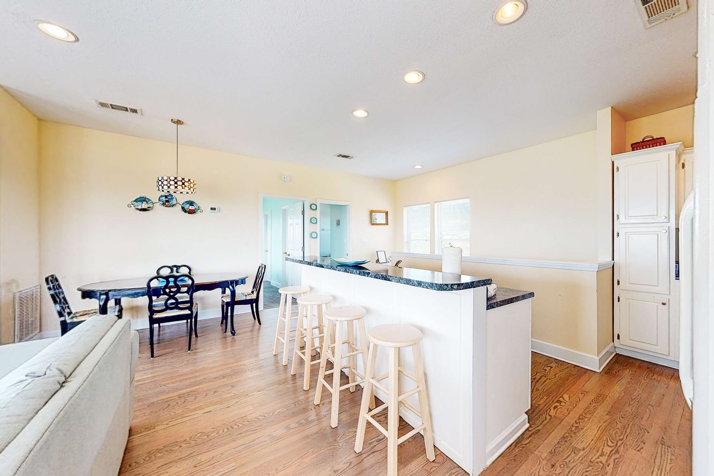 A kitchen with a central island, wooden flooring, and white cabinetry.