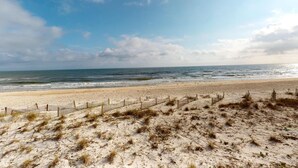 Ein Strand mit einer Holzfence und Dünen.