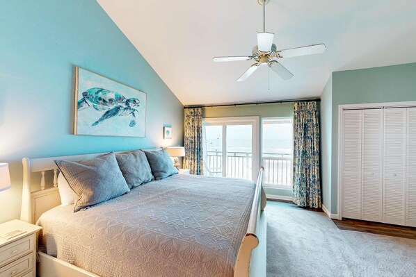 Une chambre à coucher avec un lit, un ventilateur de plafond, une fenêtre avec des rideaux et une vue sur l’extérieur.