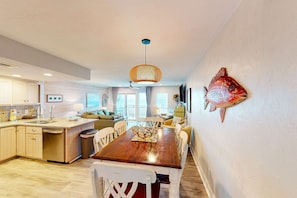 Une cuisine spacieuse avec une table à manger en bois, des chaises blanches et un ventilateur de plafond.