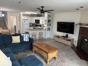 A living room with a blue sofa, wooden coffee table, and a TV. - Dog-friendly beachfront townhouse with comunity pool, washer/dryer, central AC (St. George Island)