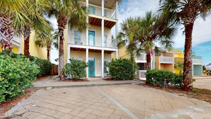 A multi-story hotel with a central courtyard, palm trees, and a tiled walkway. - Dog-friendly home near beach with pool, four balconies, WD & AC (Panama City Beach)