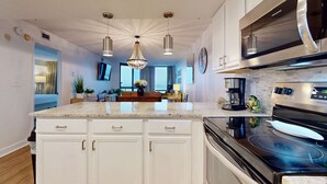 Une cuisine moderne avec des meubles blancs, une cuisinière noire et des luminaires suspendus.