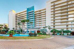 A multi-story hotel with a prominent sign reading "Sterling Shores." It features a central courtyard with a swimming pool, surrounded by palm trees and greenery. - Sterling Shores 316 (Destin)