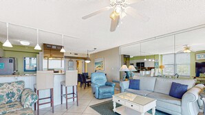 Een ruime woonkamer met een bank, fauteuils, een salontafel en een eethoek met stoelen en een tafel.