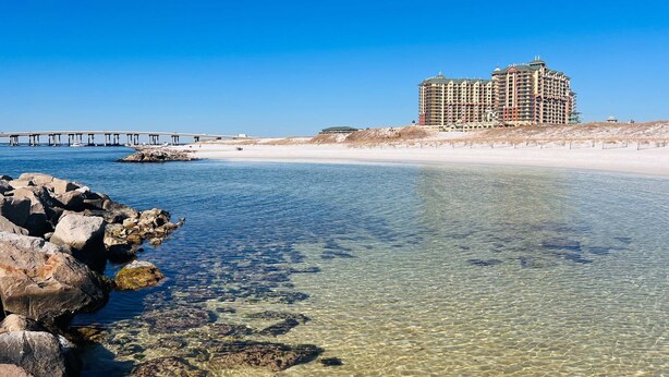 Um hotel à beira-mar com águas cristalinas, um cais e uma praia de areia.
