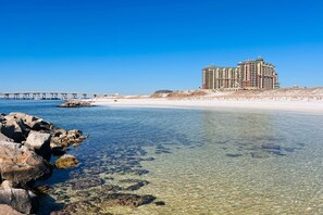 Um hotel à beira-mar com águas cristalinas, um cais e uma praia de areia.
