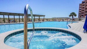Een zwembad met een jacuzzi in het midden, omringd door ligbedden en een overdekt terras.