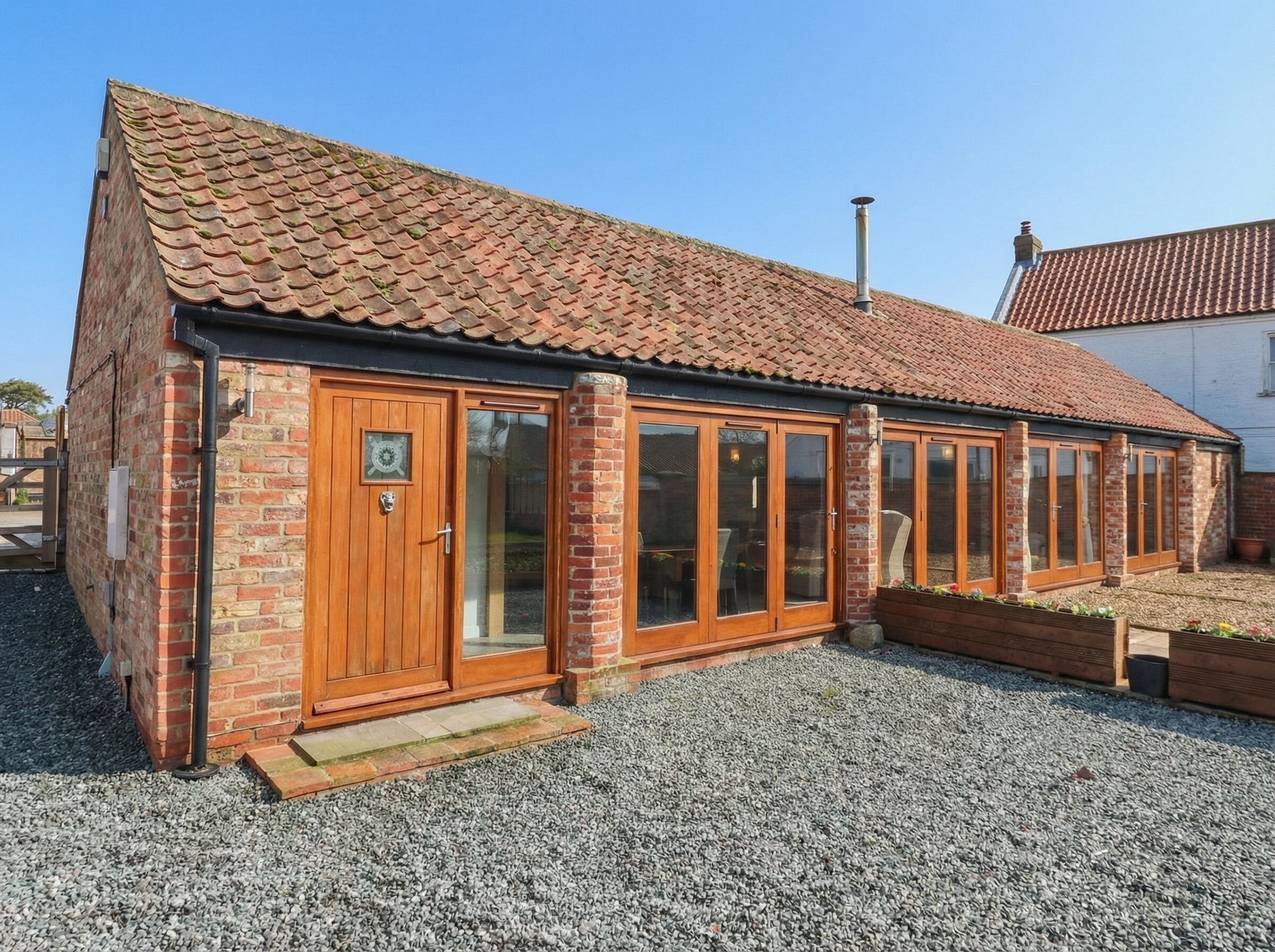 A brick building with a tiled roof, wooden doors, and large windows.
