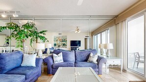 Una sala moderna con dos sofás, una mesa de centro de vidrio y una planta grande.