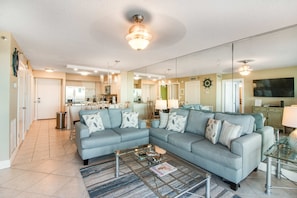 A spacious living room with a sectional sofa, a coffee table, and a TV. - Magnolia House at Destin Pointe 203 (Destin)