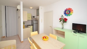 A modern kitchen with a microwave, a refrigerator, and a dining area with a table and chairs. - One-bedroom Apartment With sea View (San Michele al Tagliamento)