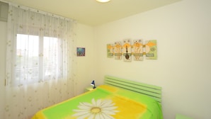 A bedroom with a bed, a nightstand, a lamp, and artwork on the wall. - One-bedroom Apartment With sea View (San Michele al Tagliamento)