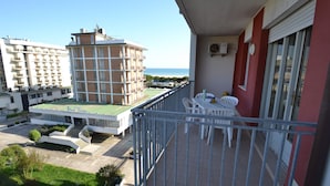 A balcony with a view of a building complex and the sea. - One-bedroom Apartment With sea View (San Michele al Tagliamento)
