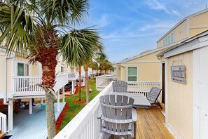 A deck with a palm tree, a lounge chair, and a sign that reads "Welcome to Beachside." - Snowbird & dog-friendly condo with 5 pools, hot tubs, golf, tennis, pickleball (Destin)