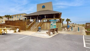 Ein Gebäude direkt am Strand mit überdachter Veranda, Holzterrasse und einem Schild mit der Aufschrift 'BAGGAGE ICE'.