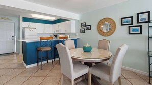 A modern kitchen with a blue accent wall, white cabinets, and a central island with bar stools. - Coastal condo with Gulf views, washer and dryer, Wifi, Community pool (Destin)
