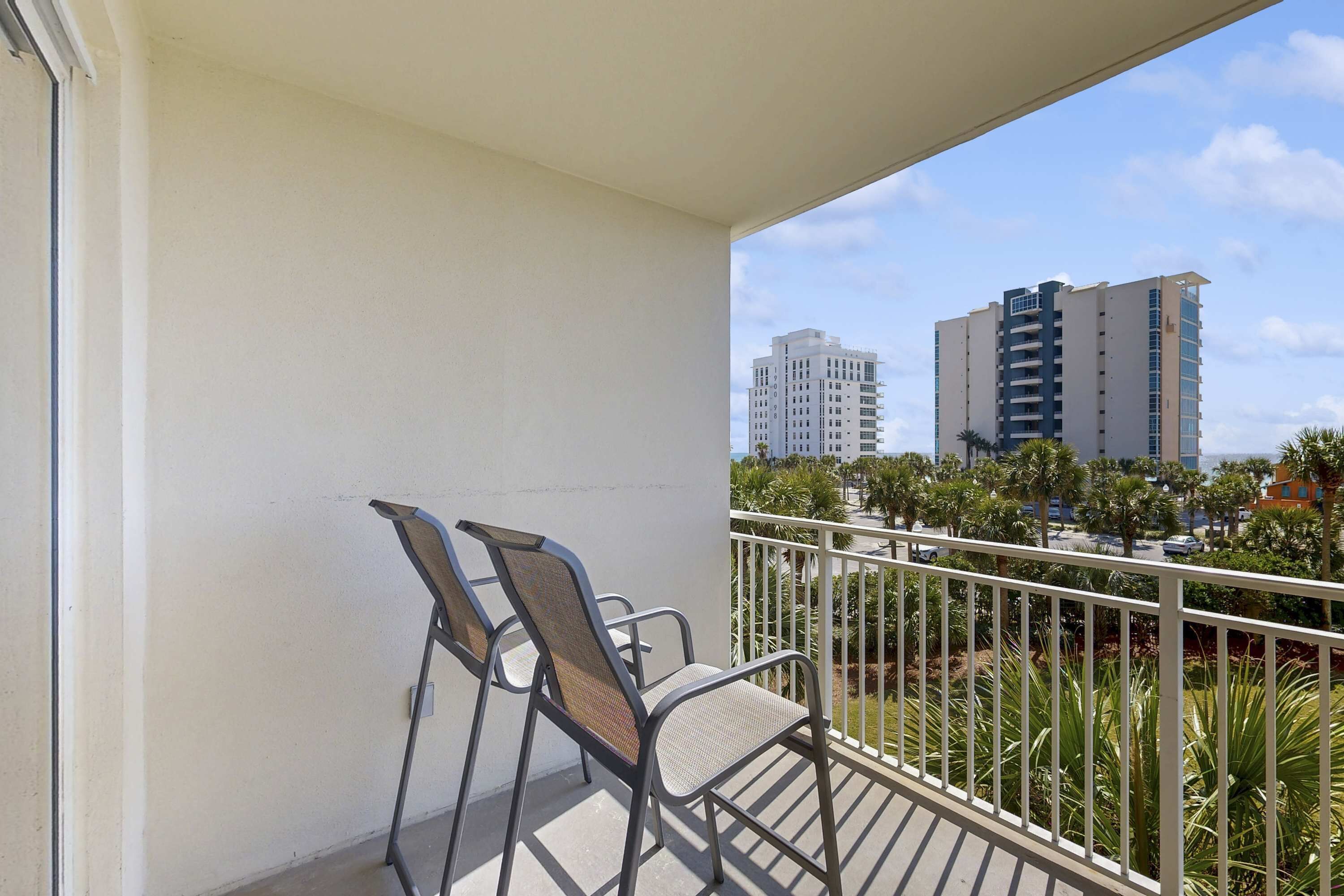 A balcony with two chairs and a view of tall buildings in the background.