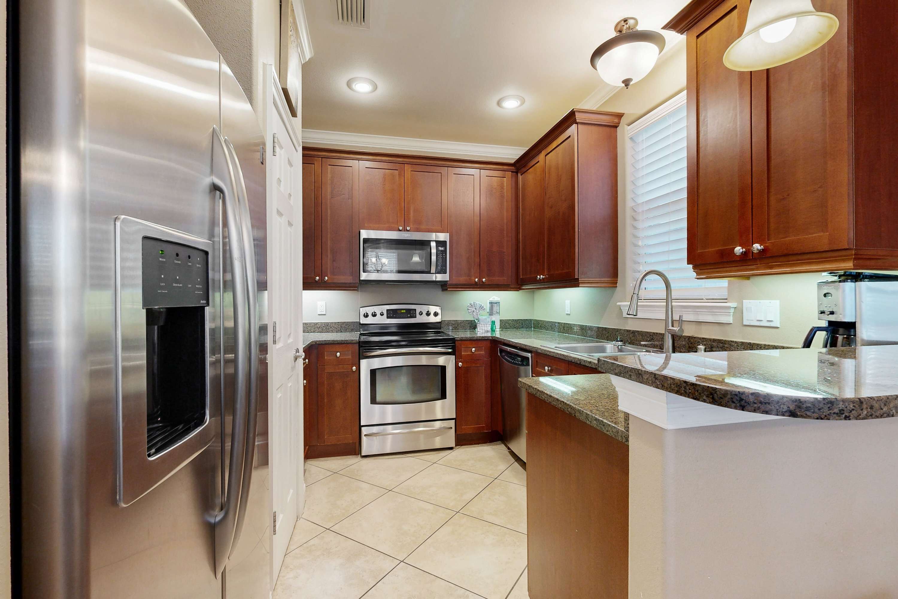 A modern kitchen with stainless steel appliances, wooden cabinets, and granite countertops.
