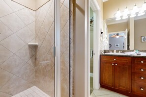 Une salle de bain avec douche, lavabo et miroir.