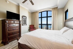 A hotel room with a large bed, a dresser, a television, a chair, and a window with a view. - Penthouse condo Emerald Grande with pools, hot tubs, gym - water view balconies (Destin)