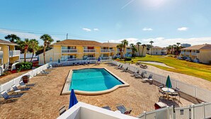 A hotel with a swimming pool, sun loungers, and a fenced patio area. - Charming condo with pool, hot tub, tennis, balcony, & W&D (Destin)