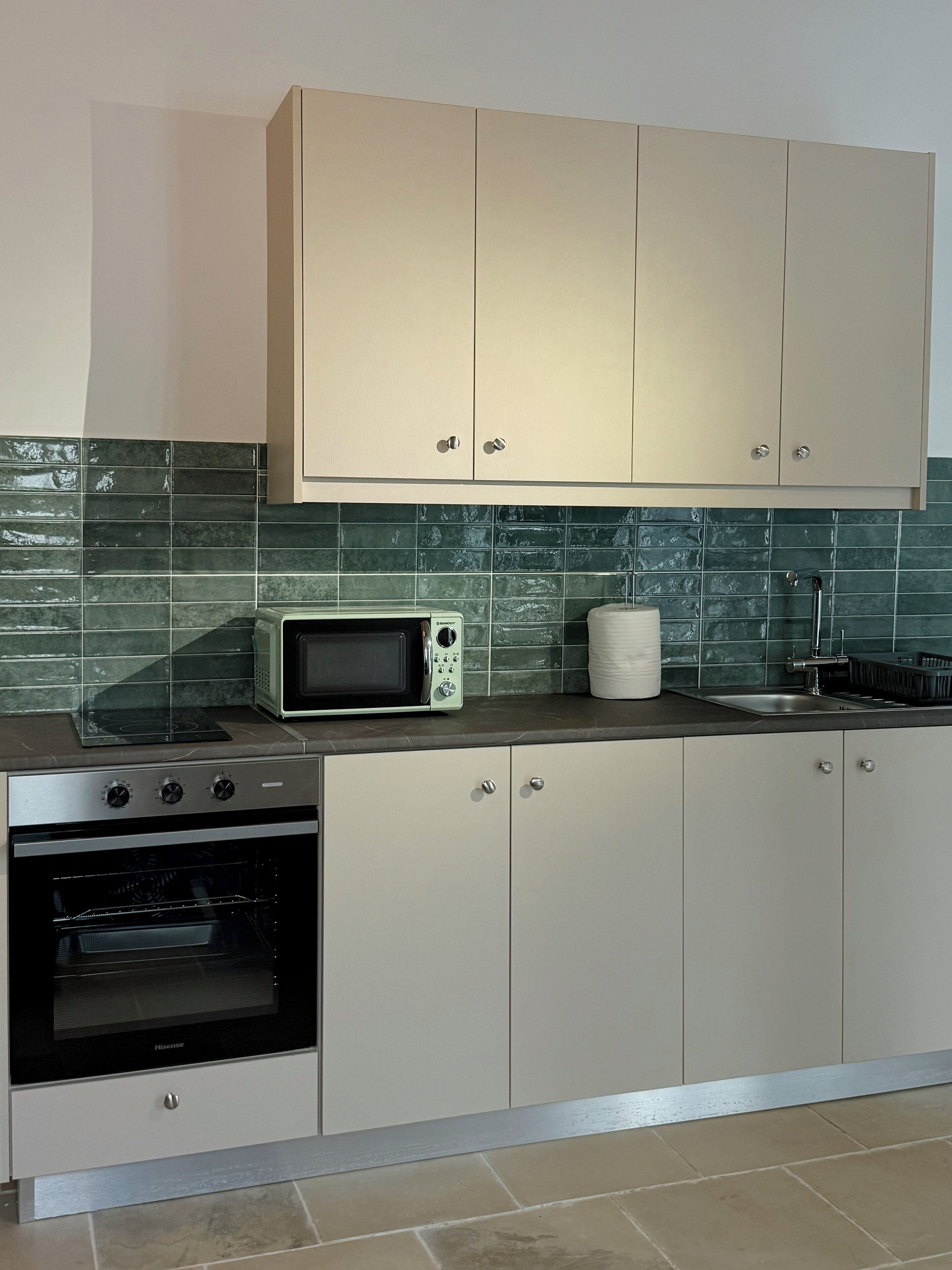 Eine Küche mit beigen Schränken, einer Mikrowelle, einem Backofen und einem Spülbecken.