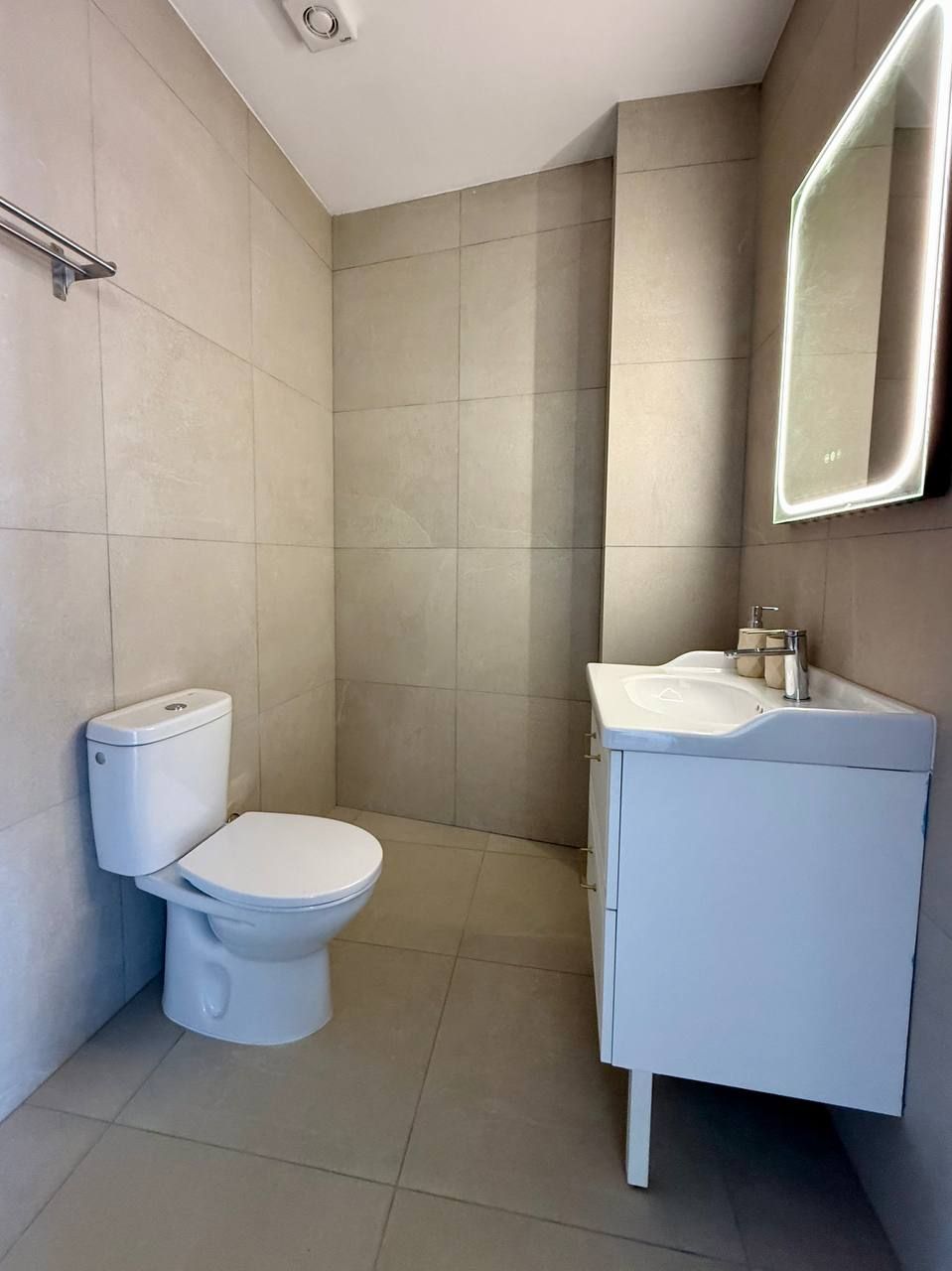 A modern bathroom with a toilet, sink, and mirror.