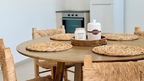 A round wooden table with woven placemats, surrounded by wicker chairs. A tray with two white jars labeled "Coffee" and "Love" is placed on the table. - Kiti Traditional Residences (Kiti)