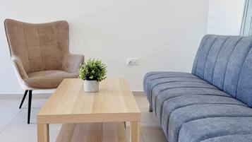 A modern living room with a wooden coffee table, a beige armchair, and a blue sofa.