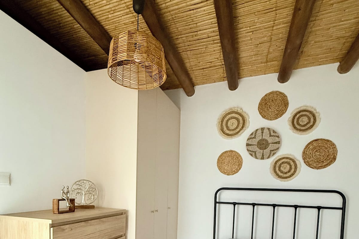 A bedroom with a bed, wooden dresser, and a ceiling fan.